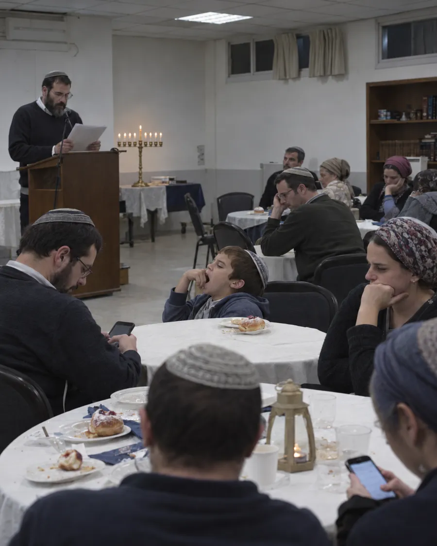 נאום ארוך בערב חנוכה: אנשים משועממים ליד השולחנות ומסתכלים בטלפונים